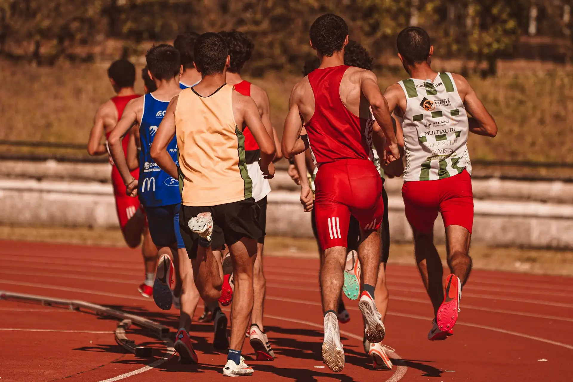 Men competing in a running event on a sunny outdoor track, showcasing athleticism and determination.